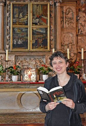 <p>Anne Grießer mit ihrem Roman vor dem Walldürner Blutaltar. Am 30. April stellt die gebürtige Walldürnerin ihr Buch im Alten Rathaus vor.</p>