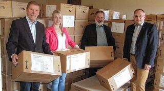 <p>Verabschiedung inmitten von Bergen von Kartons mit Büchern und Akten des Grund-buchamts der Stadt Külsheim: (von links) der bisherige Grundbuchamtsleiter Karl-Heinz Düll, Mitarbeiterin Yvonne Kaufmann, Rechtspfleger Dieter Nebel und Bürger-meister Thomas Schreglmann.</p>