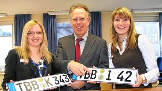 <p>Alternativ zu den bewährten Feststoffplaketten (Schild links) können die Kunden in den Zulassungsstellen des Landratsamtes nun auch Klebeplaketten erhalten (Schild rechts): Landrat Reinhard Frank freut sich mit zwei Mitarbeiterinnen der Kfz-Zulassung über das neue Angebot.</p>