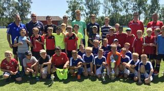 Die drei Mannschaften auf dem „Podest“: Um den begehrten Wanderpokal sind die Sieger der Grundschule Dertingen gruppiert, dahinter das Team der Grundschule Grünsfeld-Wittighausen (rote Trikots) und die drittplatzierte Grundschule aus Wertheim. Mit ihnen freuen sich die Jungschiedsrichter und die Verantwortlichen des TSV Assamstadt mit Dominik Thiel und Uwe Schultheiß (Turnierleitung).