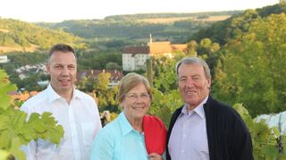 Die Wollingers sind bereits in der dritten Generation dem Winzertanz verfallen: Die Aufnahme zeigt Arnd, Helga und Ernst Wollinger (von links) in den Weinbergen über Niederstetten; im Hintergrund das Schloss.