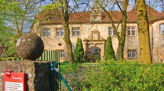 Das Wachbacher Schloss mit seinem Eingangsportal, über dem das Wappen der Herren von Adelsheim prangt. Seit 2018 gehört das Anwesen der German Property Group, die es nach eigenen Angaben sanieren will, um dort Betreutes Wohnen anzubieten. Doch negative Schlagzeilen lassen daran Zweifel aufkommen.