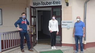 Dr. Carsten Köber, Sozialdezernentin Elisabeth Krug (Landratsamt Main-Tauber-Kreis) und Dr. Roland Rechtenwald vor dem Eingang der neuen Fieberambulanz in Bad Mergentheim.
