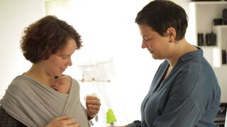 Hebamme Melanie Stier-Zink (rechts) hilft beim Anlegen eines Babytragetuchs.