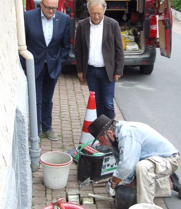 Gunter Demnig verlegt die Stolpersteine. Interessierte Beobachter sind Bürgermeister Thomas Schreglmann (links) und Alfred Bauch.