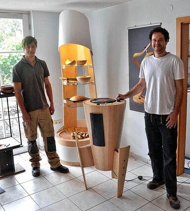 <p>Juniorchef Dominic Burger (links) mit seiner Meisterarbeit, einer Präsentiersäule mit integriertem Beamer und LED-Leuchten, sowie Markus Czink mit seinem Gesellenstück, einer Klangsäule, Schallplattenspieler, Lautsprecher und Schubfach für weitere Platten inbegriffen.</p>