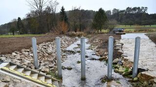 Stabile Pfosten im Brehmbach sollen mit dazu beitragen, dass Schwemmgut nicht in das Durchlassbauwerk (rechtes Bild) hineingespült wird.