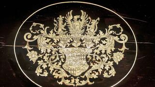 Motto und Wappen der Hohenloher „Ex flammis orior“ mit der bekrönenden Darstellung des Phoenix, der aus Flammen aufsteigt.