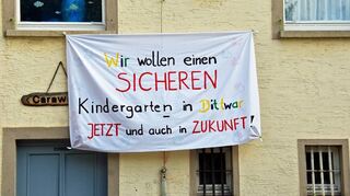 Mit einem Transparent machen Eltern in Dittwar auf den schlechten Zustand des Gebäudes aufmerksam, in dem die katholische Kindertagesstätte St. Elisabeth untergebracht ist.