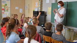 Die Viertklässler der Grundschule Nassig sitzen in Halbkreisen um die Tafel herum. Im Hintergrund der Luftfilter.