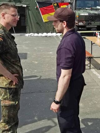 Oberstleutnant Dirck Radunz (links) im Gespräch mit einem Mitarbeiter einer Hilfsorganisation. Am Nürburgring (rechts) ist die Operationszentrale des Verbands und weiterer Hilfskräfte.