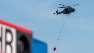 Ein Transporthubschrauber mit Löschwasserbehälter bei einer Übung für einen Brandfall: Auch in Deutschland wird ein solches Szenario regelmäßig geprobt, um für den Ernstfall gerüstet zu sein.