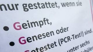 Ein Aufsteller weist Kunden auf die aktuellen Einlassregeln hin.