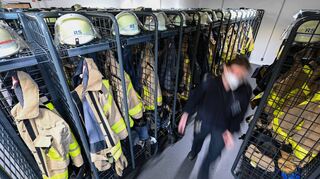 Helme und feuerfeste Bekleidung sind in diesem Raum einer Feuerwache in offenen Spinden für den Einsatz bereit.