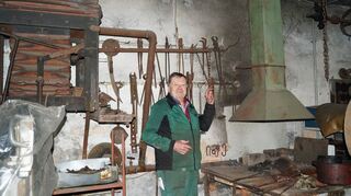 Sachs-Großneffe Gerhard Lay zieht am Blasebalg der Esse seiner Schmiede.