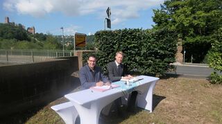 Bedeutsame Unterschrift: Nach Unterzeichnung des Staatsvertrags durch die Vertreter der beiden Bundesländer Bayern und Baden-Württemberg sowie dem Beschluss der zuständigen Kreis- und Gemeinderäte auf beiden Seiten des Mains brachten Kreuzwertheims Bürgermeister Klaus Thoma und Wertheims Oberbürgermeister Markus Herrera Torrez direkt an der bestehenden Brücke das Verwaltungsabkommen für den neuen Brückenschlag auf den Weg.