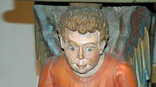 Die vier Evangelistensymbole tragen den Altartisch der Stadtkirche. Als Engel mit Buch ausgestaltet ist das Attribut des Matthäus.