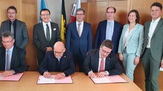 Verkehrsminister Winfried Hermann (Mitte) unterzeichnet mit den Landräten Dr. Achim Brötel (links) und Christoph Schauder (rechts) in Rosenberg den Vertrag zur Verlängerung des Probebetriebs auf der Frankenbahn – beobachtet von MdL Dr. Wolfgang Reinhart (stehend, Zweiter von links) und den fünf Bürgermeistern der Anrainerkommunen, (von links) Jürgen Galm (Osterburken), Ralph Matousek (Rosenberg), Dr. Lukas Braun (Lauda-Königshofen), Heidrun Beck (Boxberg) und Benjamin Czernin (Ahorn).