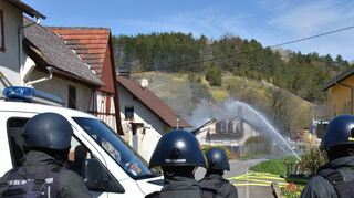 Das Areal mit den Wohngebäuden und einem Stall, der zunächst in Brand geraten war, wurde weiträumig durch die starken Polizeikräfte abgeriegelt. Das Feuer griff dann auf das Wohnhaus über.