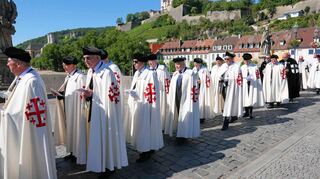 Die Ritter vom Heiligen Grab zu Jerusalem während der Reliquienprozession von der Pfarrkirche St. Burkard zum Kiliansdom. Im Hintergrund sind St. Burkard, das Käpelle und die Festung Marienberg zu sehen.