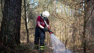 Ein Feuerwehrmann löscht einen Waldbrand. Die Gefahr für neue Brände ist aktuell sehr groß – auch im Main-Tauber-Kreis.