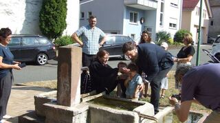 Die evangelische Pfarrerin Heike Kuhn tauft ein Kind mit dem Wasser desKülsheimer Boxhagel-Brunnens.