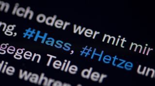 Auf dem Bildschirm eines Smartphones sieht man die Hashtags Hass und Hetze in einem Twitter-Post.