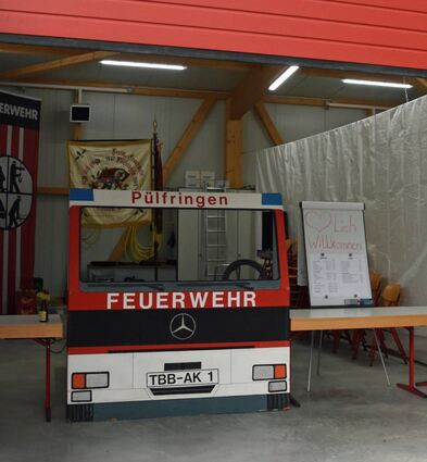 Ein Blick in die neue Fahrzeughalle mit einem „Placebo“-Einsatzfahrzeug, das beim Fest als Kassenhäuschen diente. Dahinter ist die historische Flagge zu sehen.