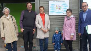 Gabriela Fischer-Rosenfeld (links), Benjamin Doth und Anette Weigler (alle drei vom Kinderschutzbund Neckar-Odenwald-Kreis) ließen ein Schild am Unterstellgebäude der „Alla hopp“-Anlage aufstellen, das auf den „Platz der Kinderrechte hinweist. Bürgermeister Roland Burger (rechts) lobte die Idee. Zum Fototermin gesellte sich eine zufällig anwesende Mutter mit ihrem Kind.
