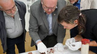 Kirchengemeinderatsmitglied Harald Stuka, Pfarrer Burkhard Keck und Julia Tauber vom Landesamt für Denkmalpflege begutachten den Inhalt der Zeitkapsel vom Turm der Bergkirche Laudenbach.