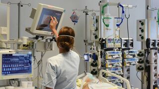 Auf der Intensivtherapie-Station steht eine Mitarbeiterin am Bett einer Patientin. Auch in den Kliniken der Region steigt wieder die Zahl der Corona-Patienten.