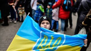Ein Junge steht mit der ukrainischen Fahne auf dem Freiheitsplatz in Cherson.