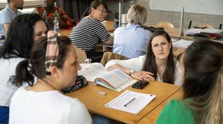 Die Leiterin eines Deutschkurses für Einwanderer im Gespräch mit Schülerinnen. Die Nachfrage nach entsprechenden Kursen wächst mit den steigenden Flüchtlingszahlen und muss von den Volkshochschulen trotz angespannter finanzieller und personeller Situation bewältigt werden.