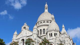 Bei Sonneneinstrahlung hellweiß präsentiert sich die Kirche Sacre-Coeur auf dem Montmartre hoch über Paris. Mehr als 40 Jahre dauert ihr Bau.