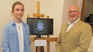 In einem Video in der Ausstellung zeigt der junge Künstler Immanuel Maria Gans, wie seine ausgestellten digitalen Gemälde entstehen. Bürgermeister Roger Henning freut sich, dass man dem jungen Künstler eine Möglichkeit bieten konnte, sein Werk zu präsentieren.