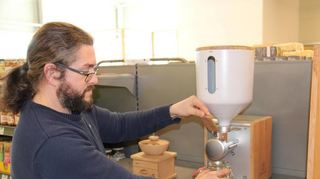 Firmenchef Stefan Bauer vom Biomarkt Beerenbauer an der Nussmusmaschine, die mit wechselnden Mischungen befüllt wird.