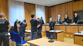 Bei Prozessbeginn werden der Angeklagten die Handschellen abgenommen. Links ihr mitangeklagter Sohn.