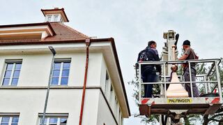 Mitarbeiter des Igersheimer Bauhofs bringen die kupferne Zeitkapsel in luftige Höhe auf das Dach des Gesundheitszentrums, wo sie fest verankert wird.