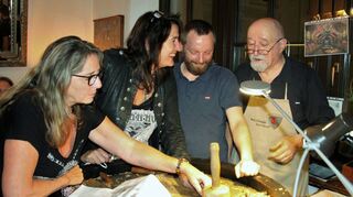 Bildhauer, Holzschnitzkünstler und DJ Heinz A. Theobald aus Lauda (rechts) sowie Assistent und designierter Nachfolger Sascha Bartmann gemeinsam mit Besucherinnen bei einer „Wood-Rock-Weinprobe“ in Würzburg.