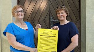 Thesenanschlag im Neckar-Odenwald-Kreis: Bettina Zeus und Silke Becker (von links) mit dem gelben Plakat vor ihrer Mörtelsteiner Dorfkirche.