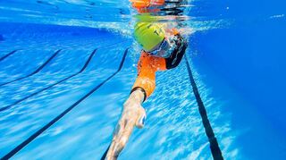 Ein Sportler schwimmt im Neoprenanzug durchs Becken.
