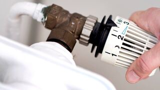 Eine Frau dreht am Thermostat eines Heizkörpers. Das Stadtwerk Tauberfranken als Grundversorger musste 2022 unzählige Bürger notversorgen.