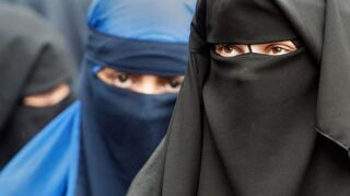 Vollverschleierte Frauen schauen auf einer Kundgebung in Offenbach durch die Schlitze ihrer Nikabs.