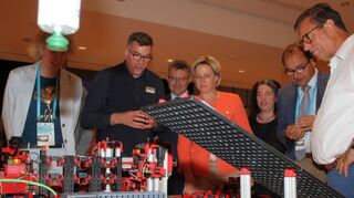 Ministerin Dr. Nicole Hoffmeister-Kraut (im roten Blazer) informiert sich am Stand der Dualen Hochschule Baden-Württemberg über Robotik.