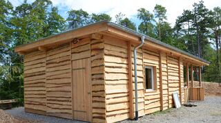 Der triste, graue Container wurde mit Holz aus heimischen Wäldern zu einer schicken Schutzhütte verkleidet. Der derzeit noch geschotterte Bereich wird mit Hackschnitzeln aufgeschüttet.
