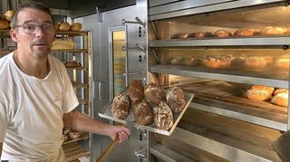 Bäckermeister Udo Wassum von der Landbäckerei Schlär holt das frischgebackene Brot aus dem Ofen.