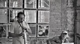 Chris Baumann und Michael Schmitt bereicherten die Vernissage mit ihren speziellen Musikbeiträgen. Im Hintergrund sind die Werke von Uwe Stephan zu sehen.