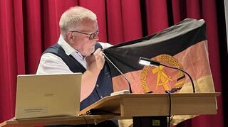 Der Journalist Eberhard Schellenberger wurde zeitweise wie ein Staatsfeind ständig observiert. Beim Vortrag in Lauda zeigte er auch eine Originalflagge der DDR, die bis zum letzten Moment am Grenzübergang flatterte.