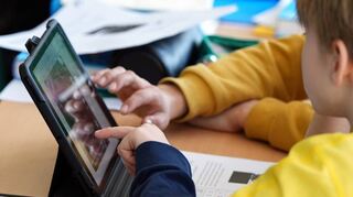 Schüler lösen im Unterricht an einem Tablet eine Aufgabe.