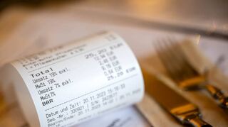 Eine Rechnung mit Umsatzsteuer und Mehrwertsteuer liegt auf der Speisekarte eines Restaurants.